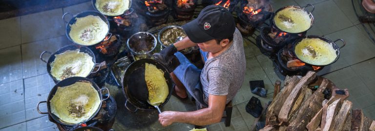 Man cooking bánh xèo, a traditional Vietnamese stuffed rice pancake